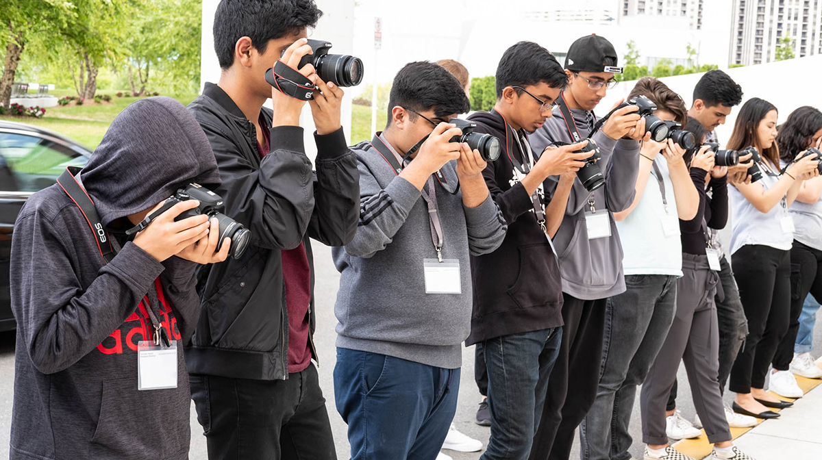 Young photographers standing in a line taking a photo.
